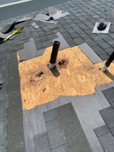 A Shingle Roof Repair Company removing shingles from vent pipe